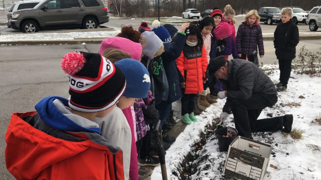 Grade 4 students planting flower bulbs with Mr. Paas.