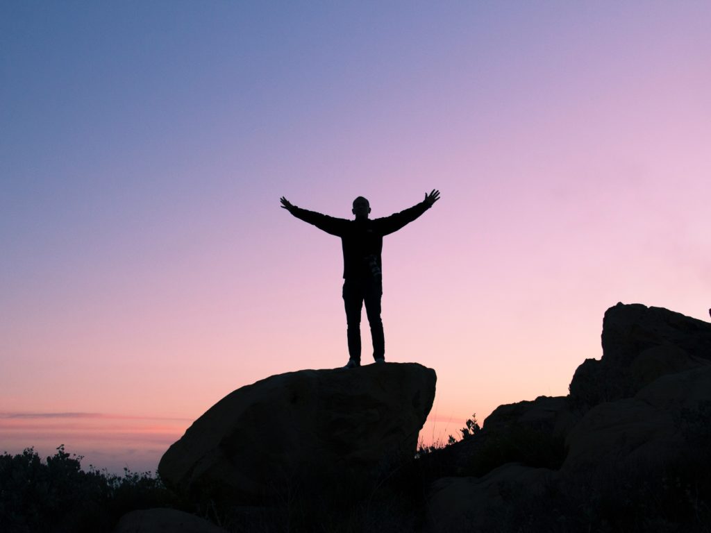 Man standing on a rock in front of a sunset