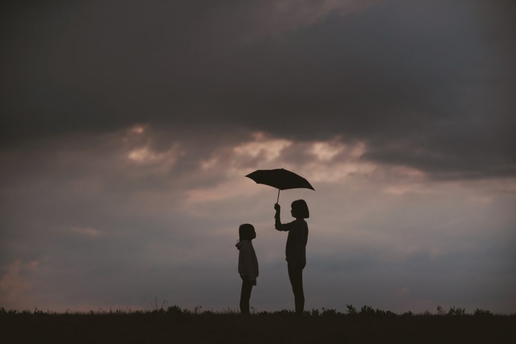 Girl holding up umbrella for a child