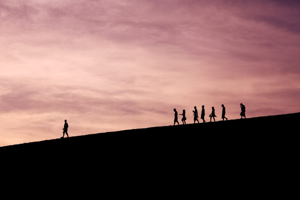 silhouette of people walking down a hill