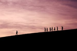 silhouette of people walking down a hill