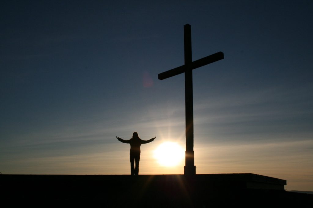sunset and person beside cross